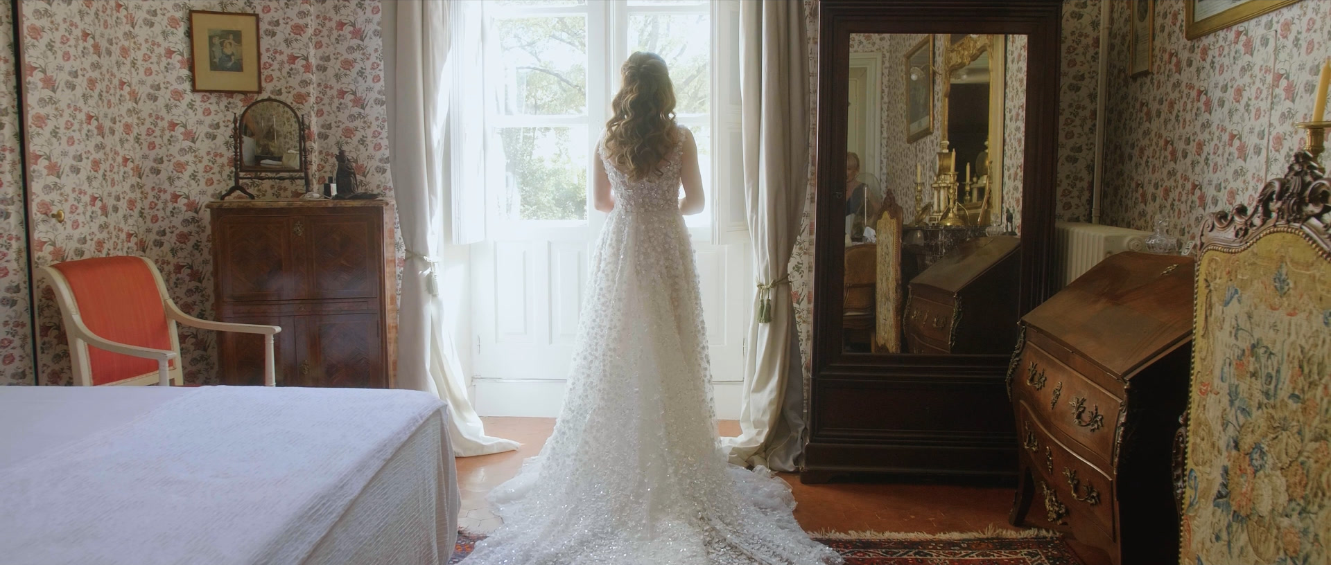 La mariée de dos face à la fenêtre, dans une chambre de château, quelques minutes avant la cérémonie